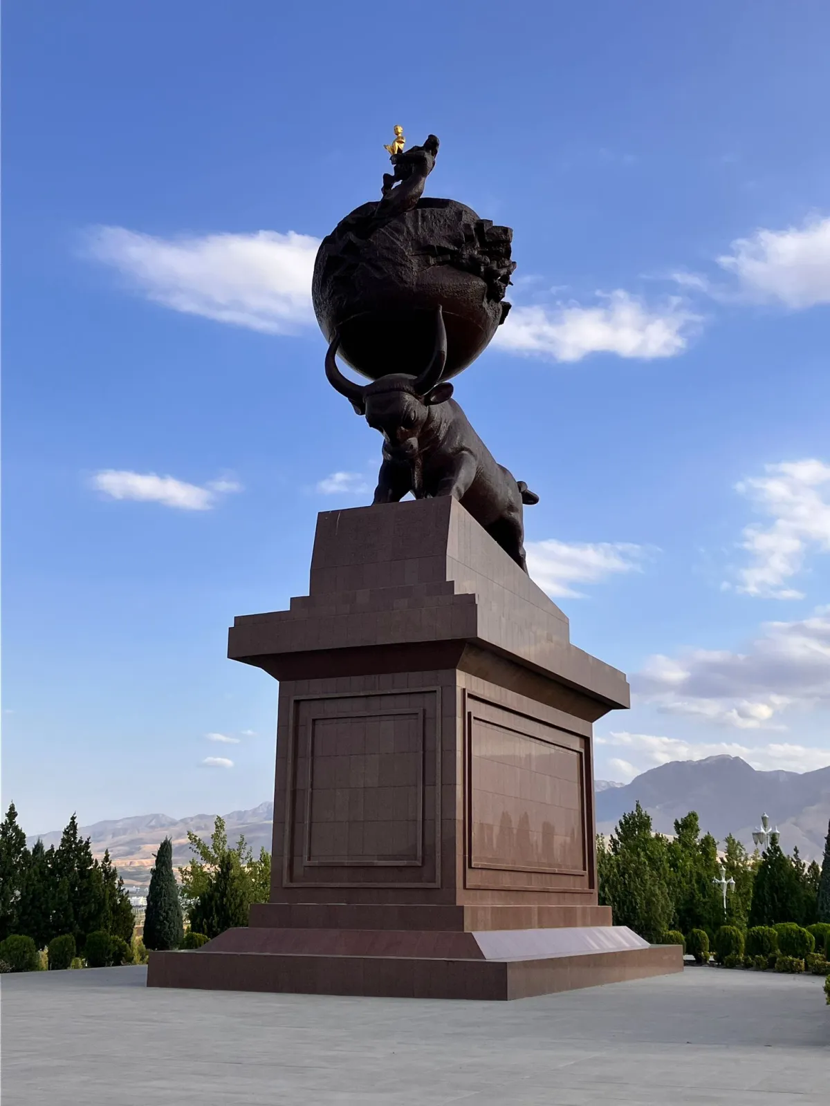 Bronze monument of a powerful bull holding a globe with a golden child on top, in the memorial complex of Ashgabat