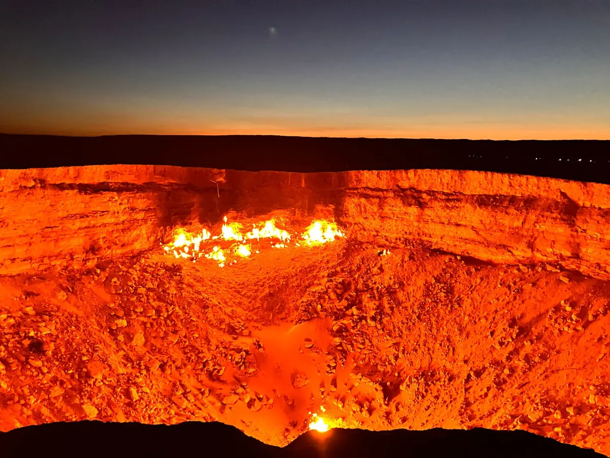 The Darvaza gas crater blazing with orange fire against the sunset sky in the Karakum Desert