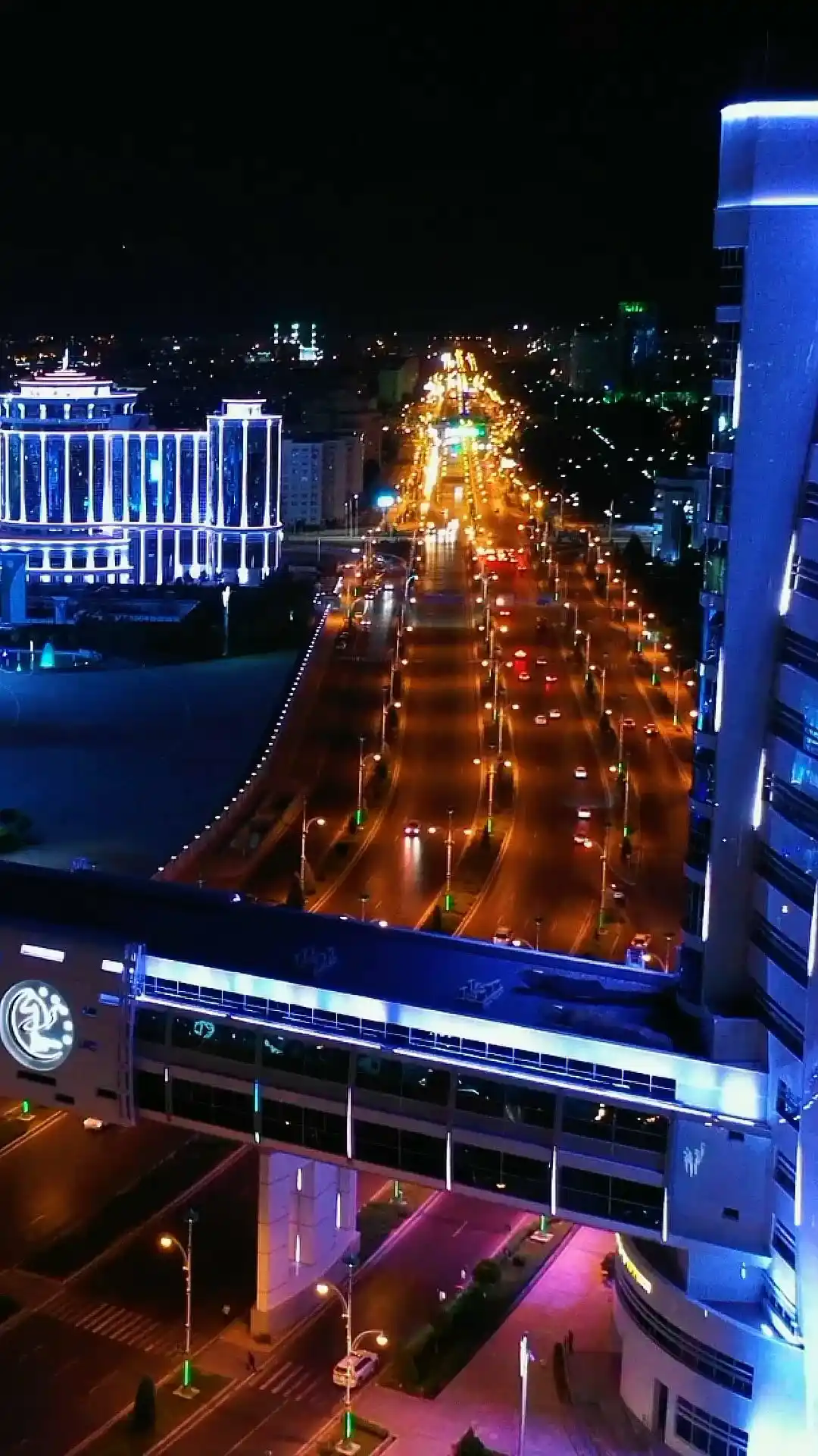 Panorama notturno di Ashgabat con boulevard illuminati, architettura moderna e un ponte pedonale in vetro — tour del Turkmenistan | TM Tourism